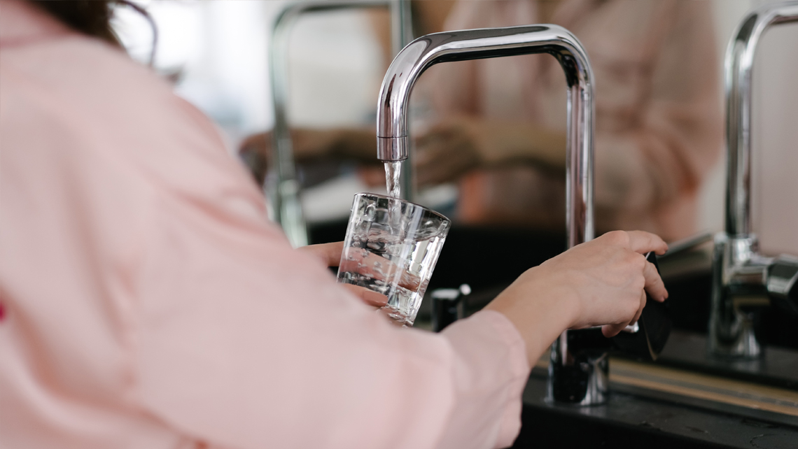 A person taking water from a kitchen tap.