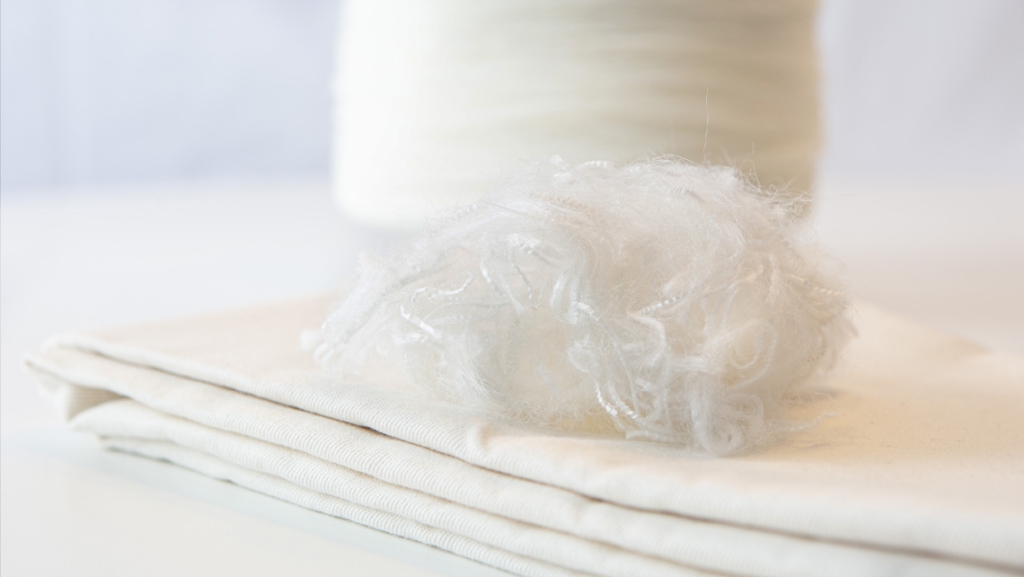 crimped white cellulosic fibers on a stack of fabric