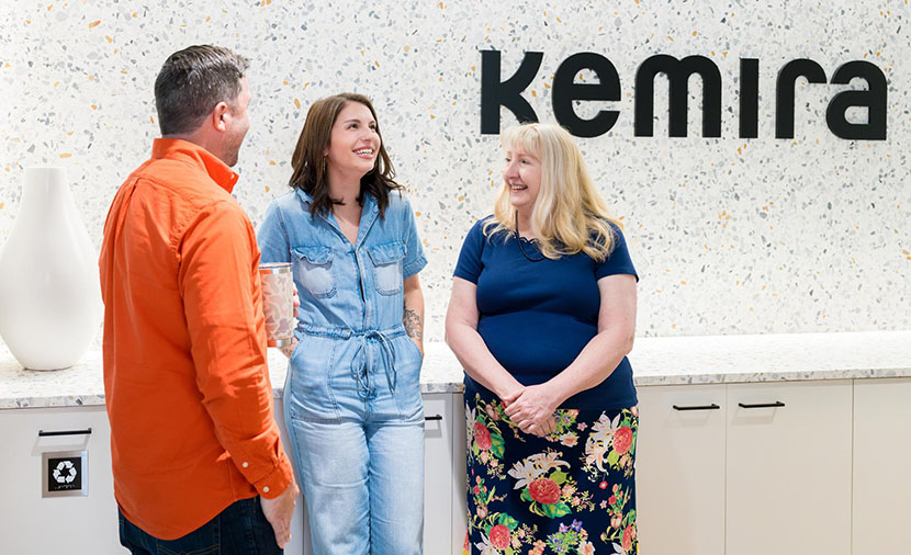 A group of people talking in from of a Kemira sign.
