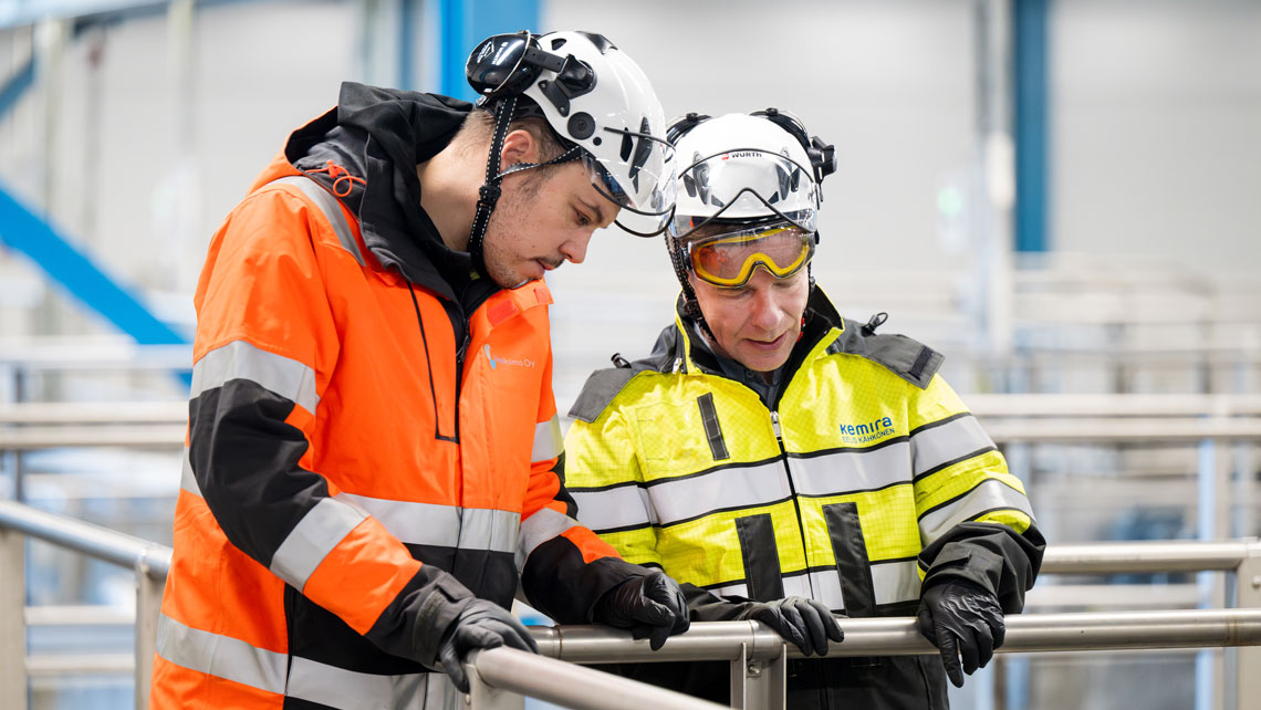 Two workers in safety gear talking at wastewater treatment plant